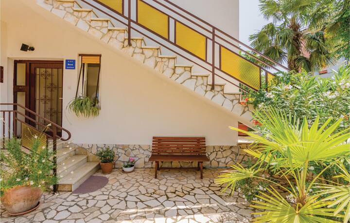 Entrance to the apartment with four small steps, garden greenery, and a bench nearby